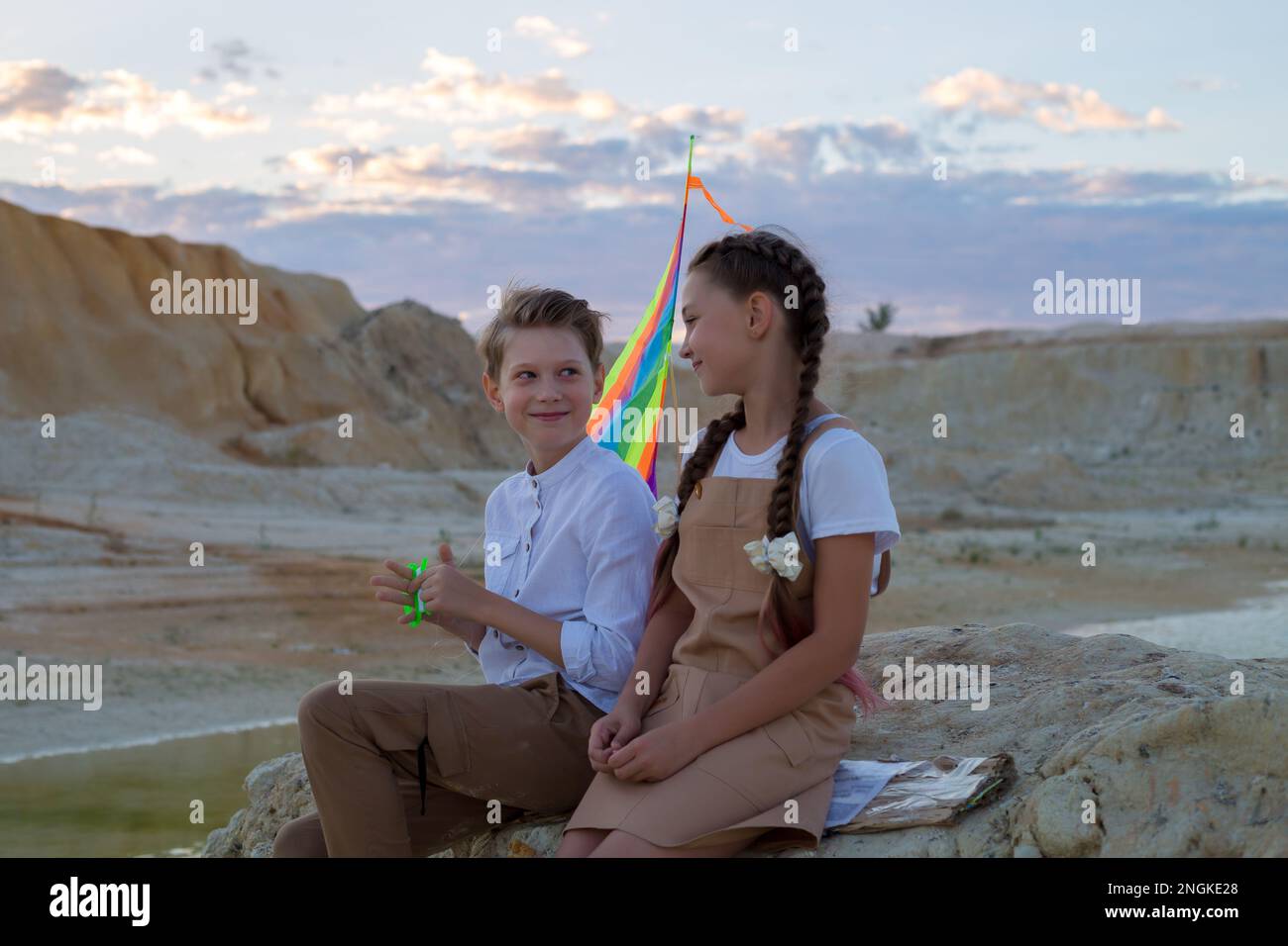 A boy and a girl 8-9 years old with kite are having fun talking on mountain. Stock Photo
