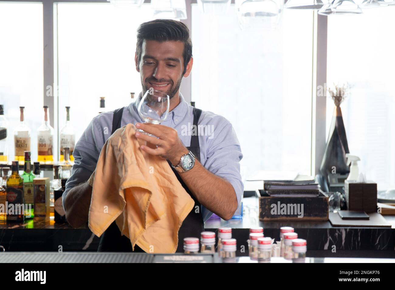 Young caucasian man is bartender cleaning and wipe glass with professional at counter, portrait handsome male preparation glass or wineglass, barman s Stock Photo