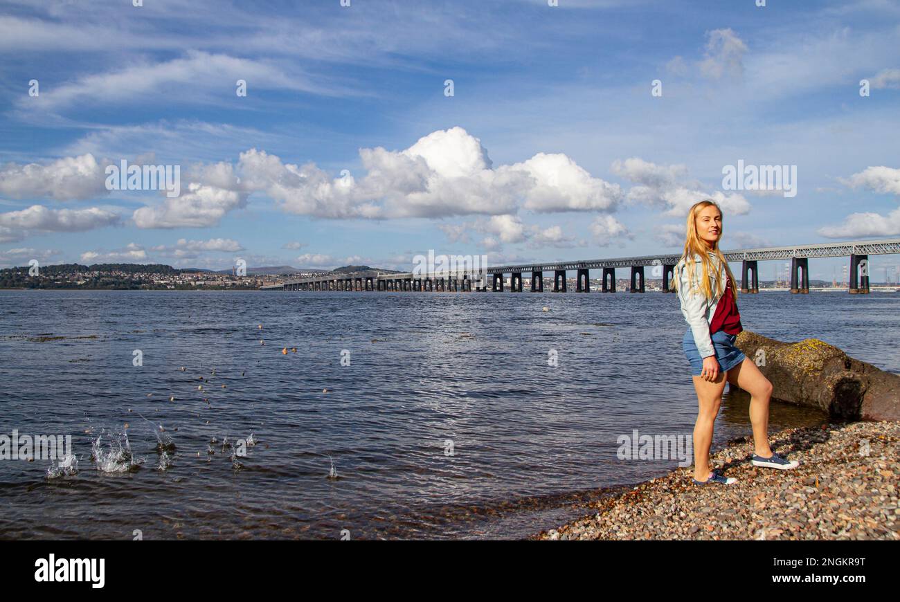 On a beautiful October day in Wormit Beach, Fife, Rhianna Martin throws pebbles over her head into the River Tay, Scotland Stock Photo