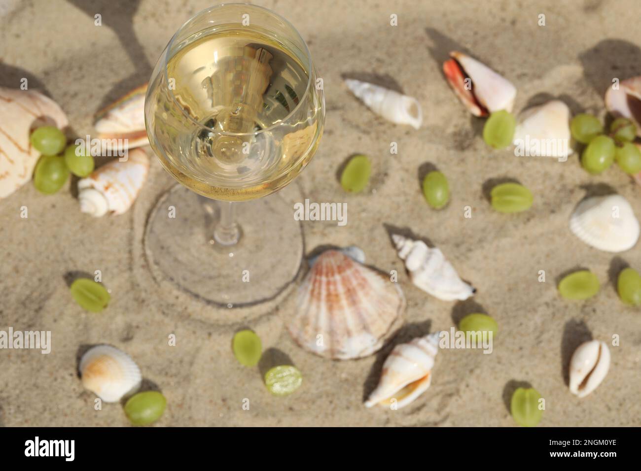 glass of white wine on sand as background with shells Stock Photo - Alamy