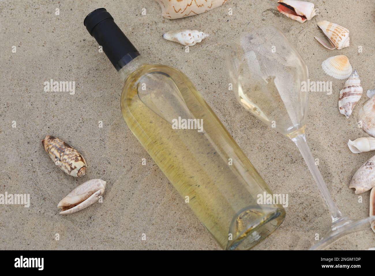 glass of white wine on sand as background with shells Stock Photo - Alamy