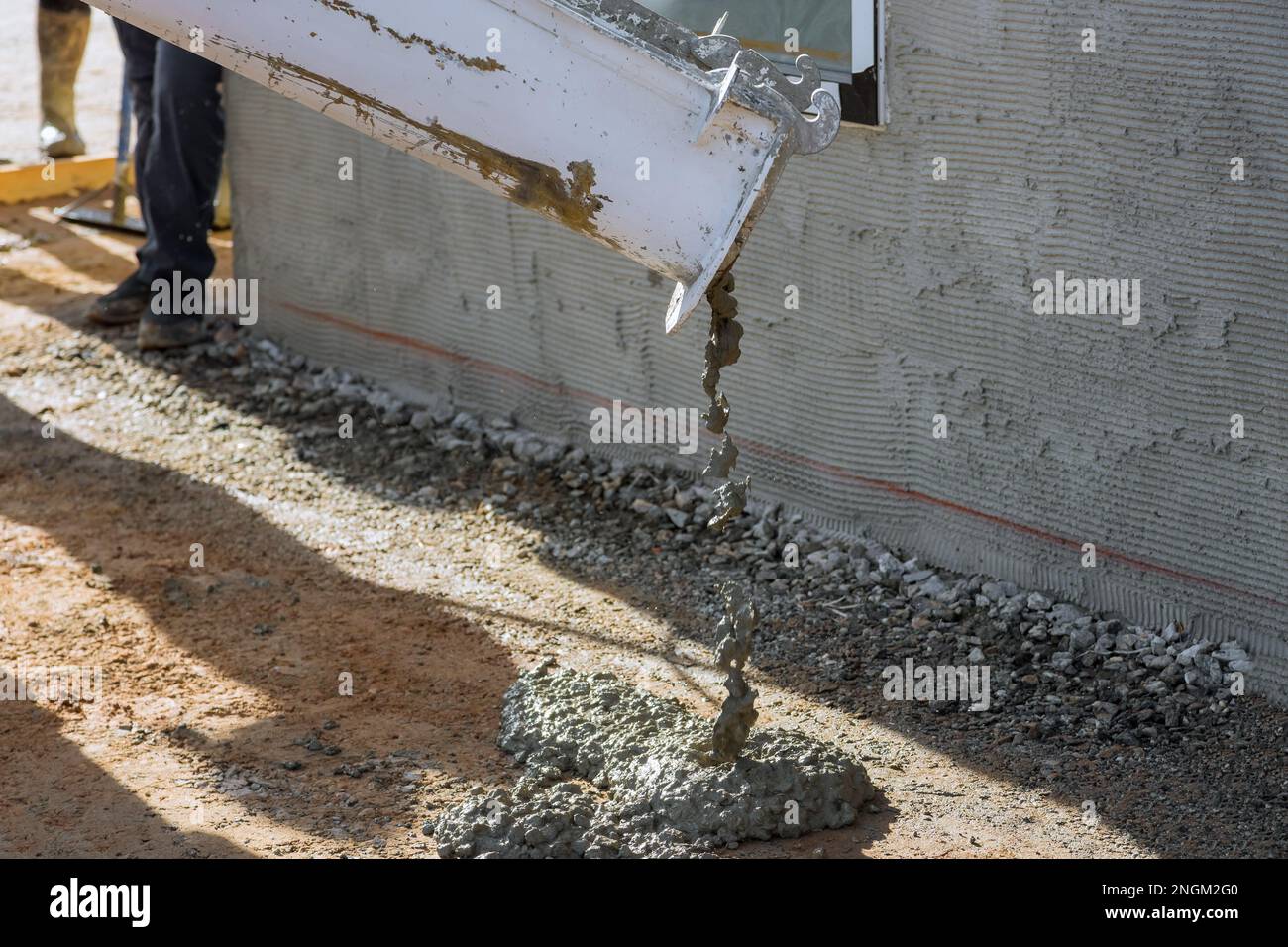 As concrete mixing truck pours concrete for pavement surrounding newly