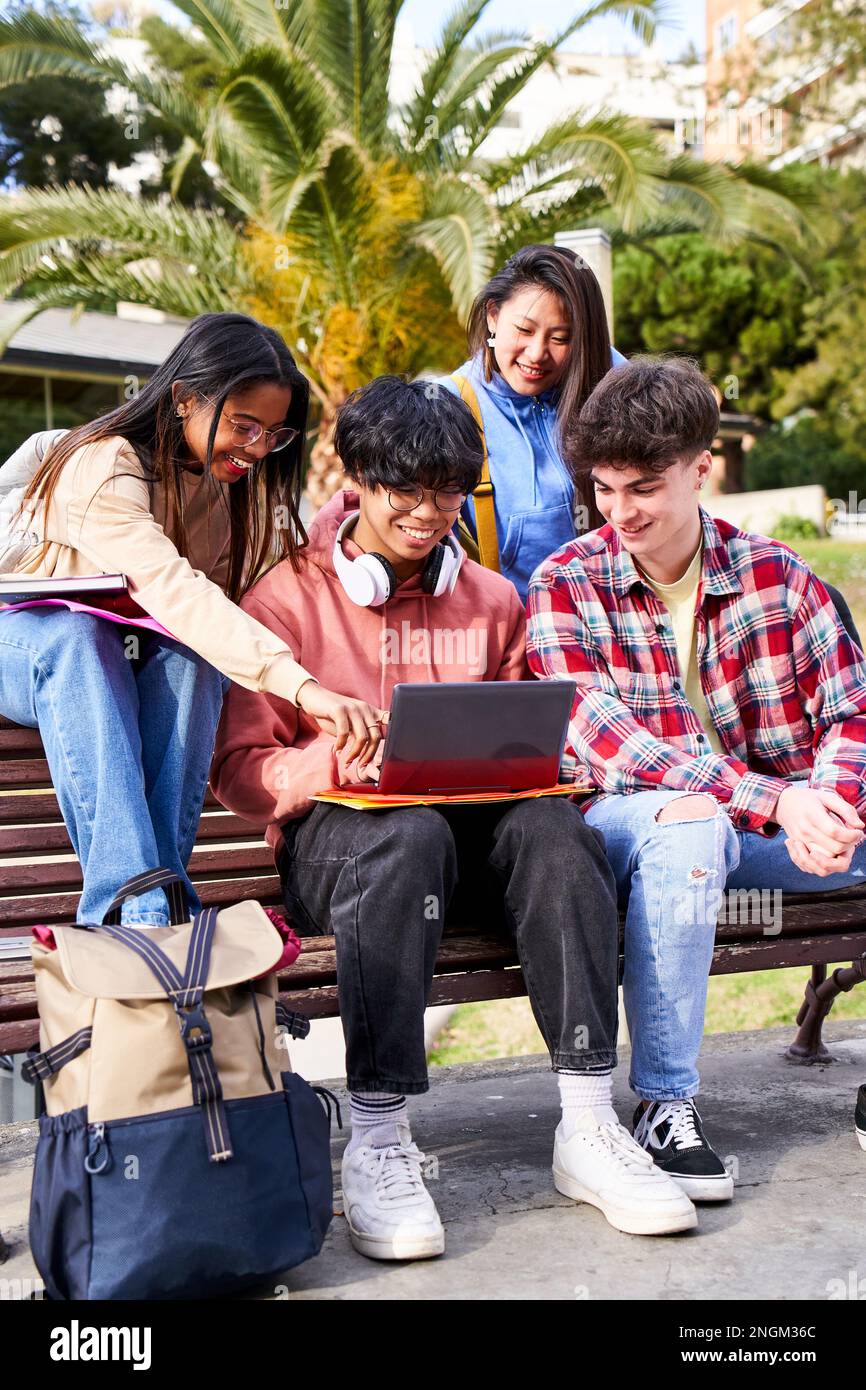 Vertical young international college students reading books and studying on laptop. People outdoors. Stock Photo