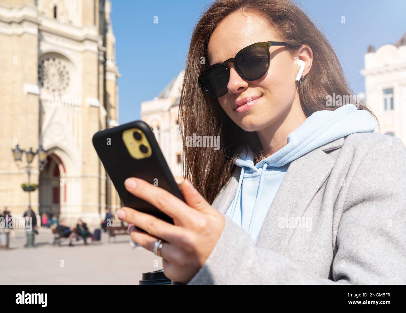 Woman with sunglasses looking at screen of her mobile phone while