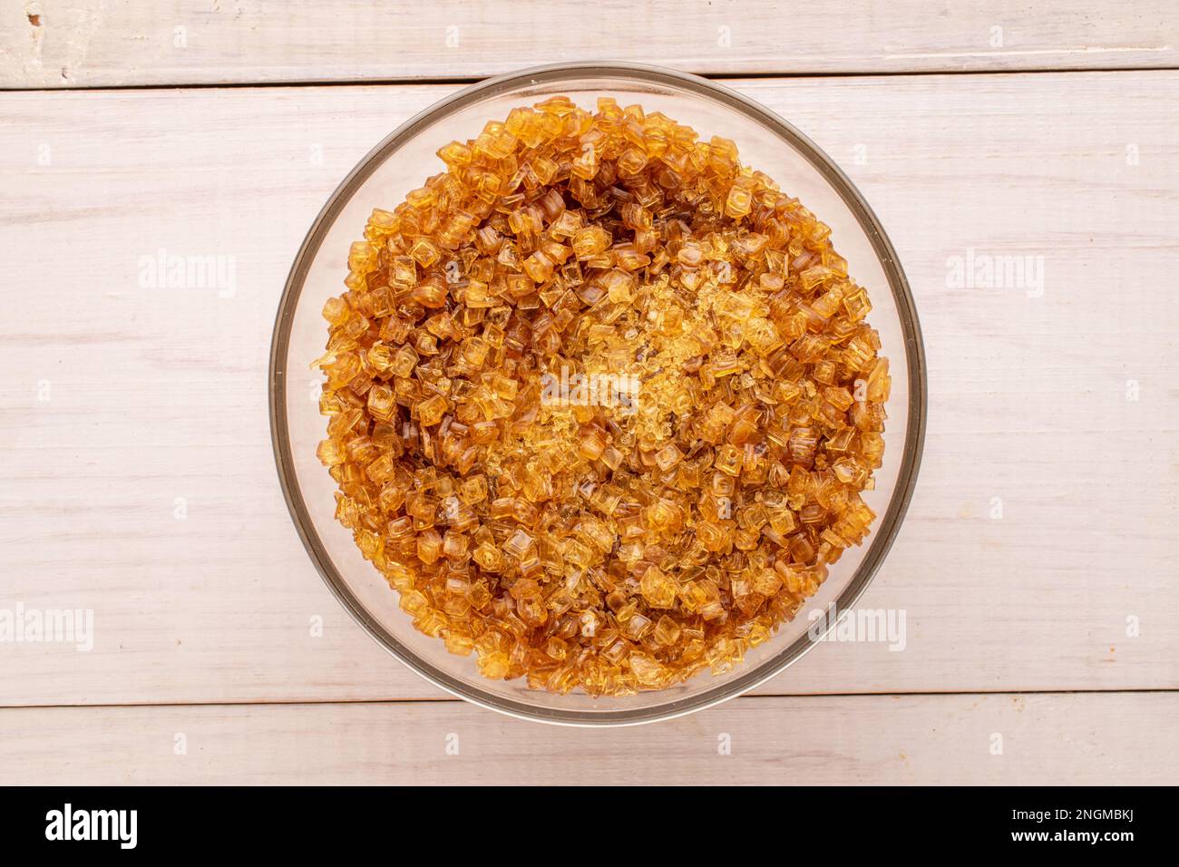 Yellow gelatin granules in a glass plate on a wooden table, macro, top view. Stock Photo