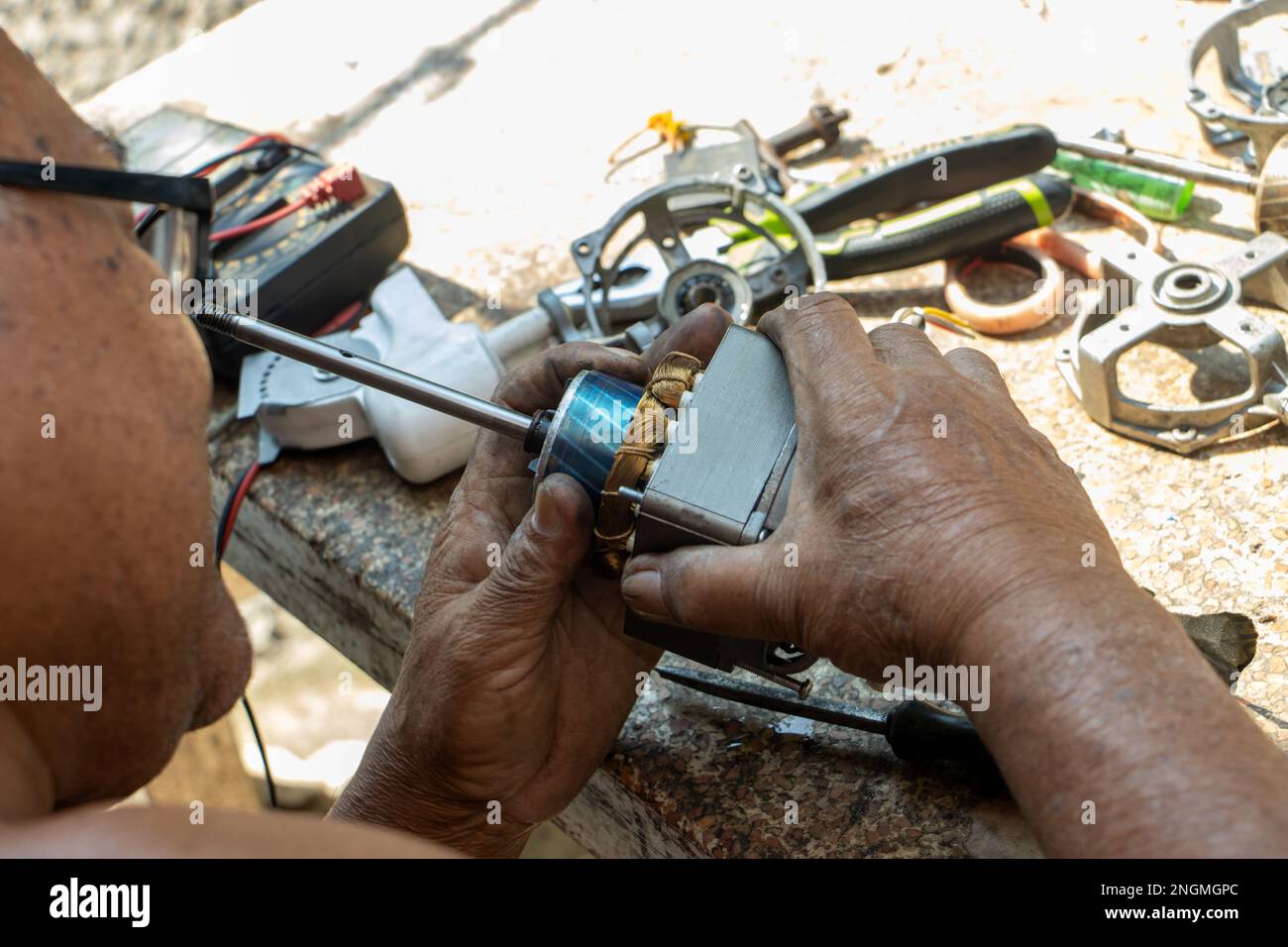 SAMUT PRAKAN, THAILAND, FEB 05 2022, A man works to repair a fan at a garden table Stock Photo