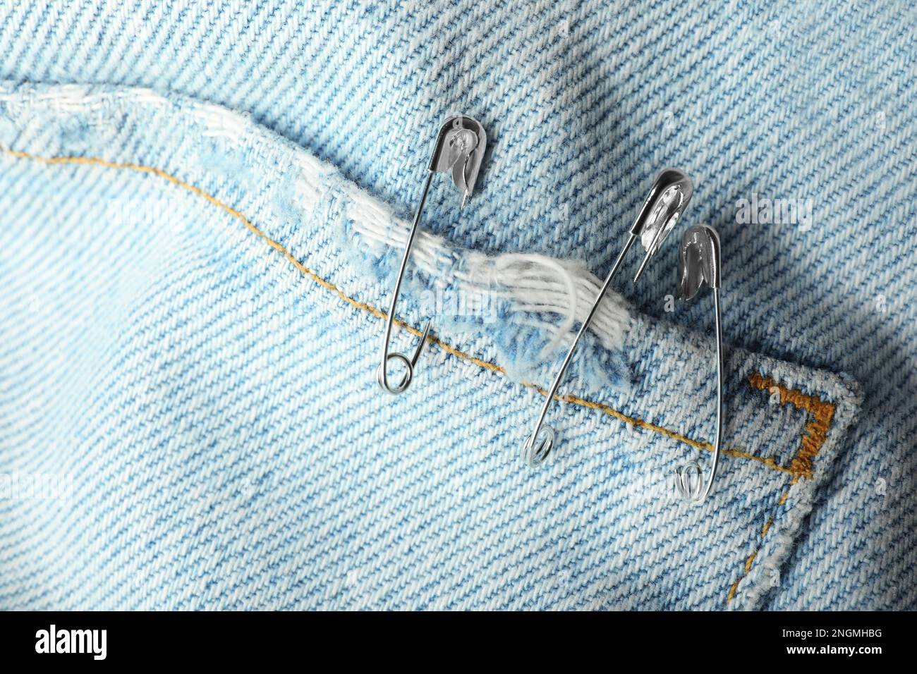 Metal safety pins on denim fabric, closeup Stock Photo Alamy