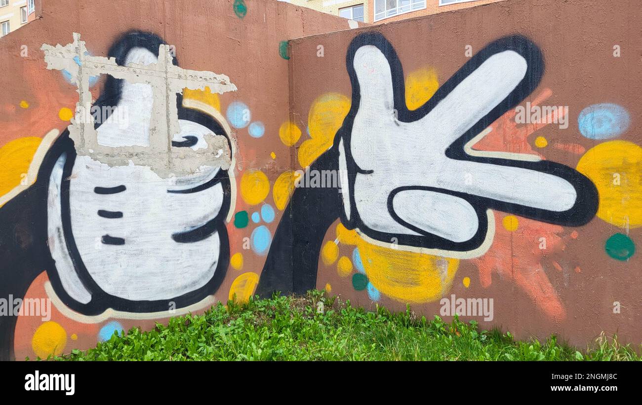 On the street, colored graffiti is painted on the brown wall of the house. Stock Photo