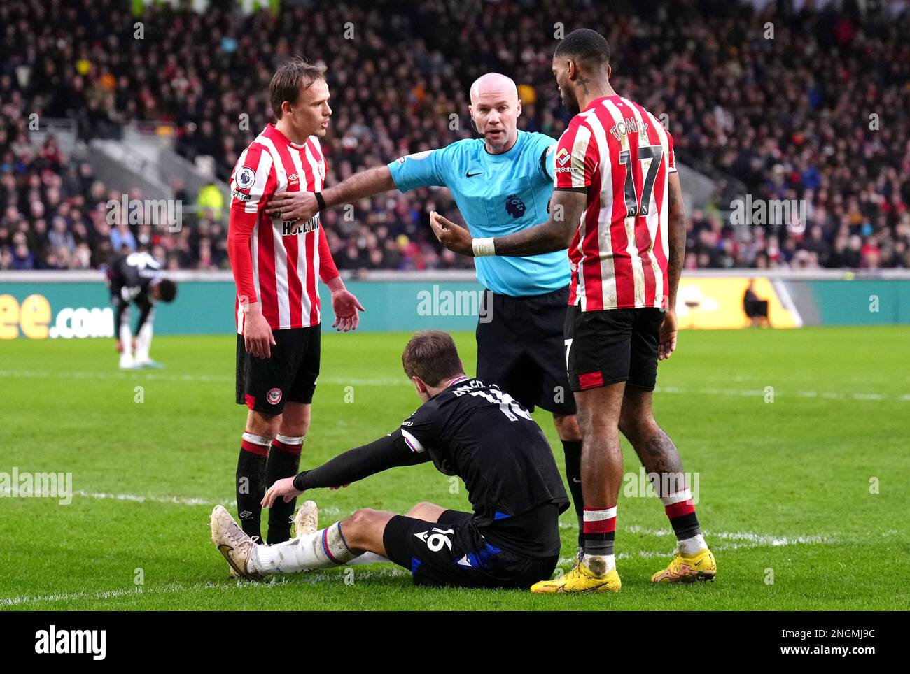 Brentford players speak with referee Paul Tierney (centre) as Crystal Palace's Joachim Andersen sits on the floor during the Premier League match at the Gtech Community Stadium, London. Picture date: Saturday February 18, 2023. Stock Photo