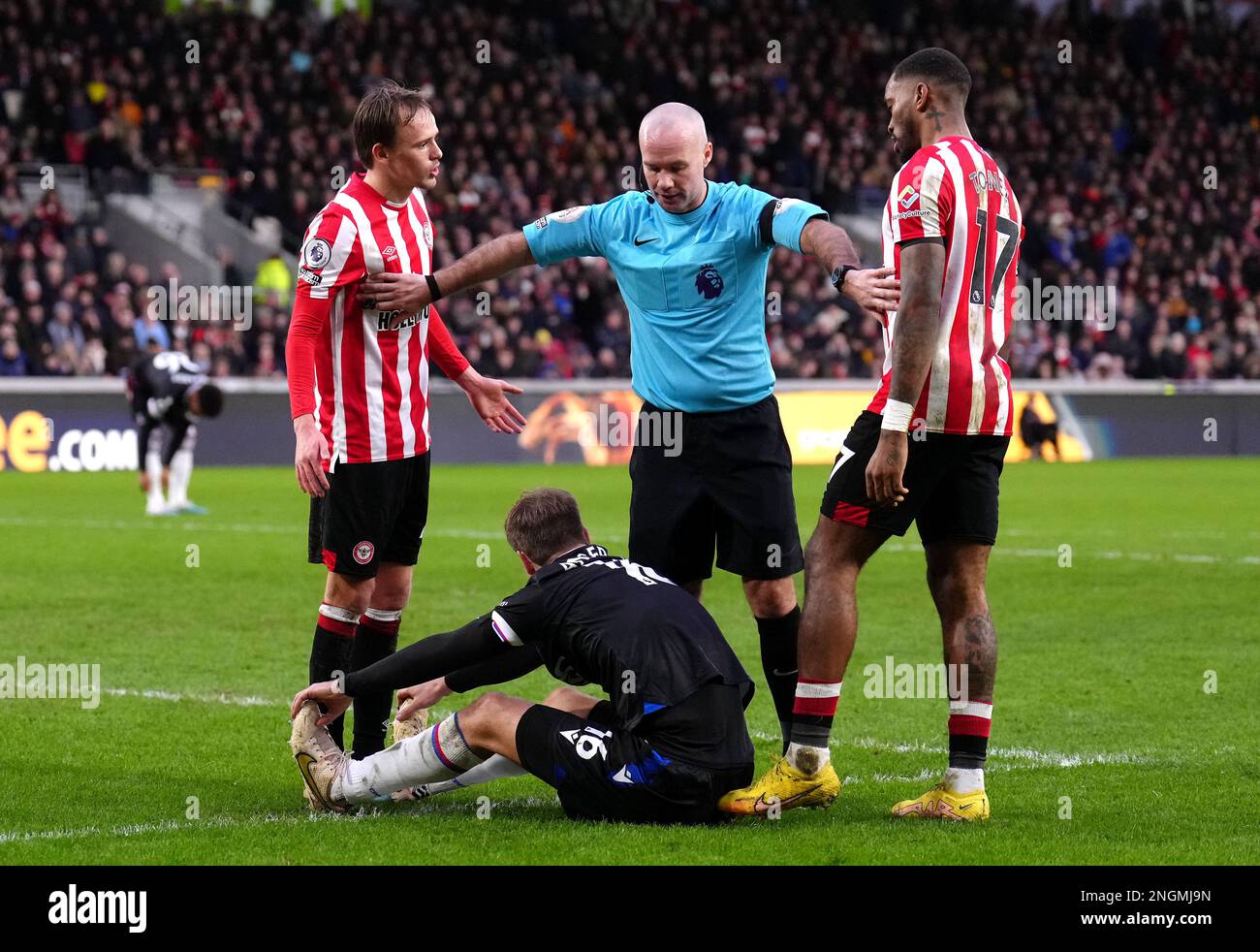 Brentford players speak with referee Paul Tierney (centre) as Crystal Palace's Joachim Andersen sits on the floor during the Premier League match at the Gtech Community Stadium, London. Picture date: Saturday February 18, 2023. Stock Photo