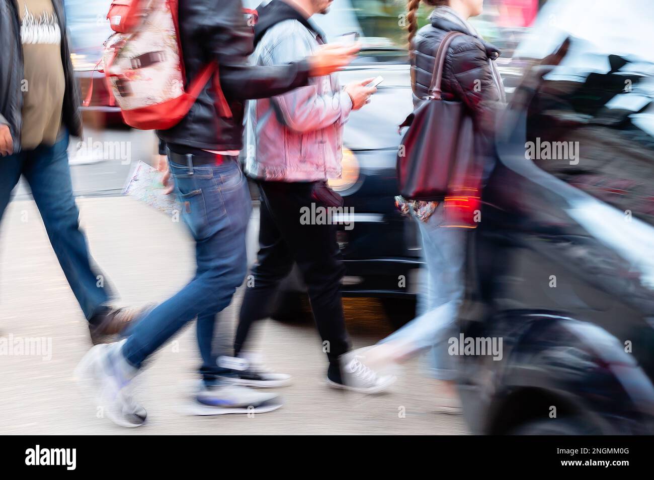image with motion blur of people crossing a city street between the ...