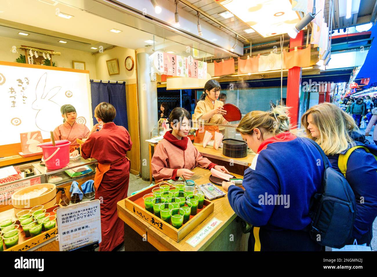 Tokyo, The popular Asakusa shrine and Sensoji temple. Caucasian woman buying green drink from food and drink shop on Nakamise dori, street. Night time Stock Photo