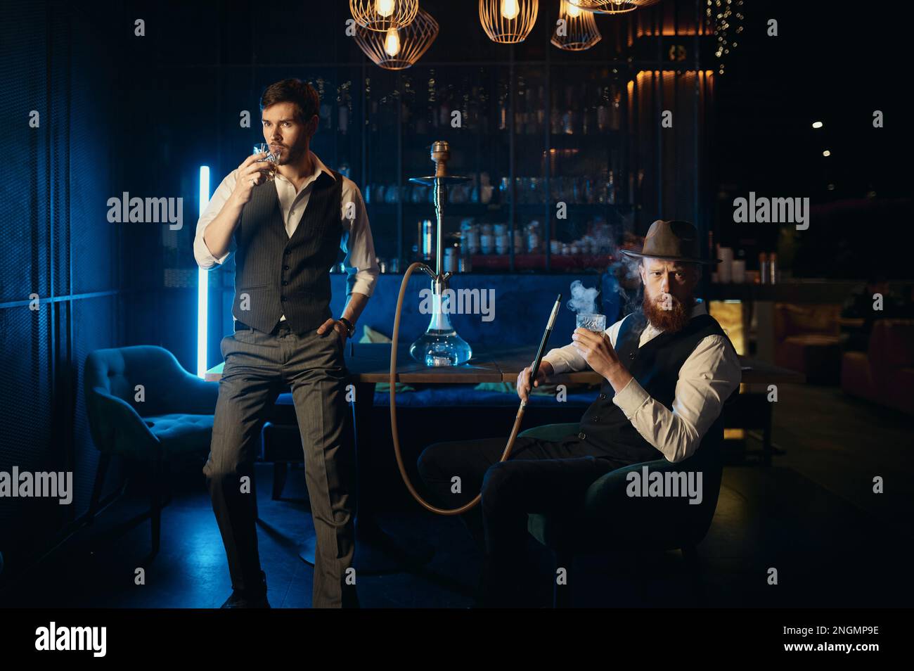 Serious guys smoking hookah while rest in pub Stock Photo
