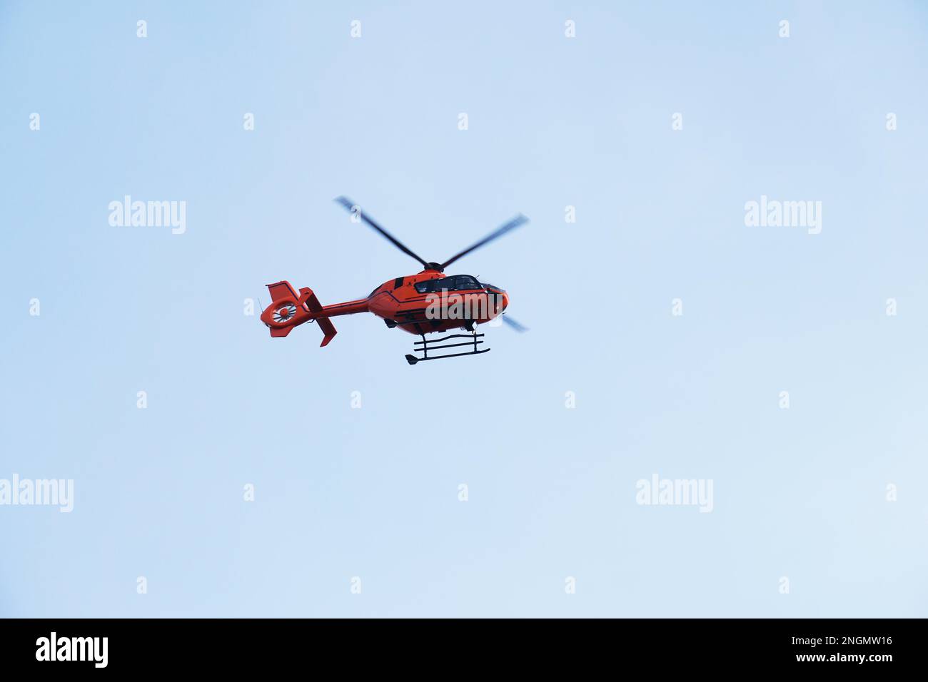 Rescue Helicopter or Air ambulance - red air medical services heli copter midair against blue sky Stock Photo