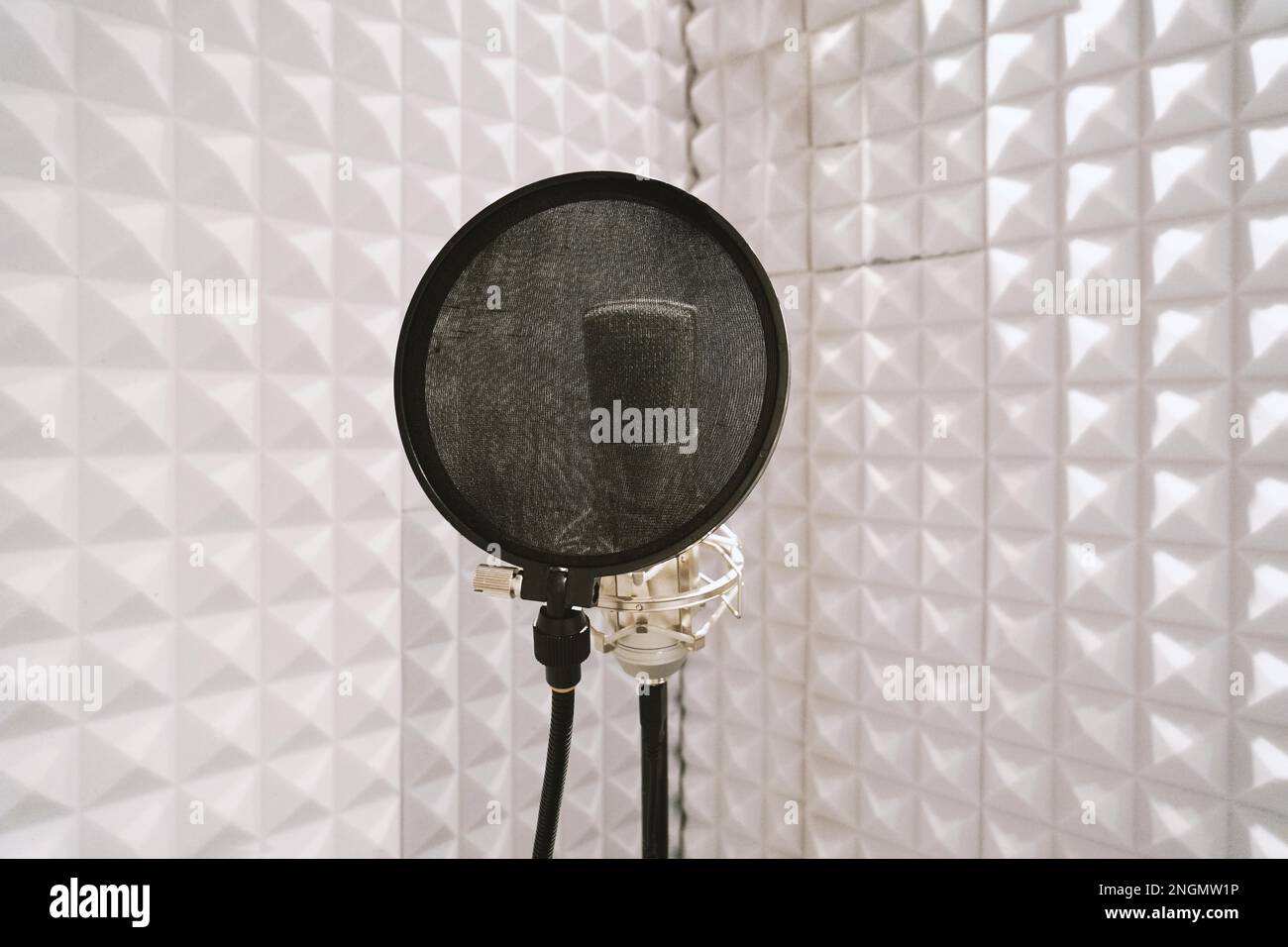 microphone with pop filter on mic stand in soundproof isolation booth