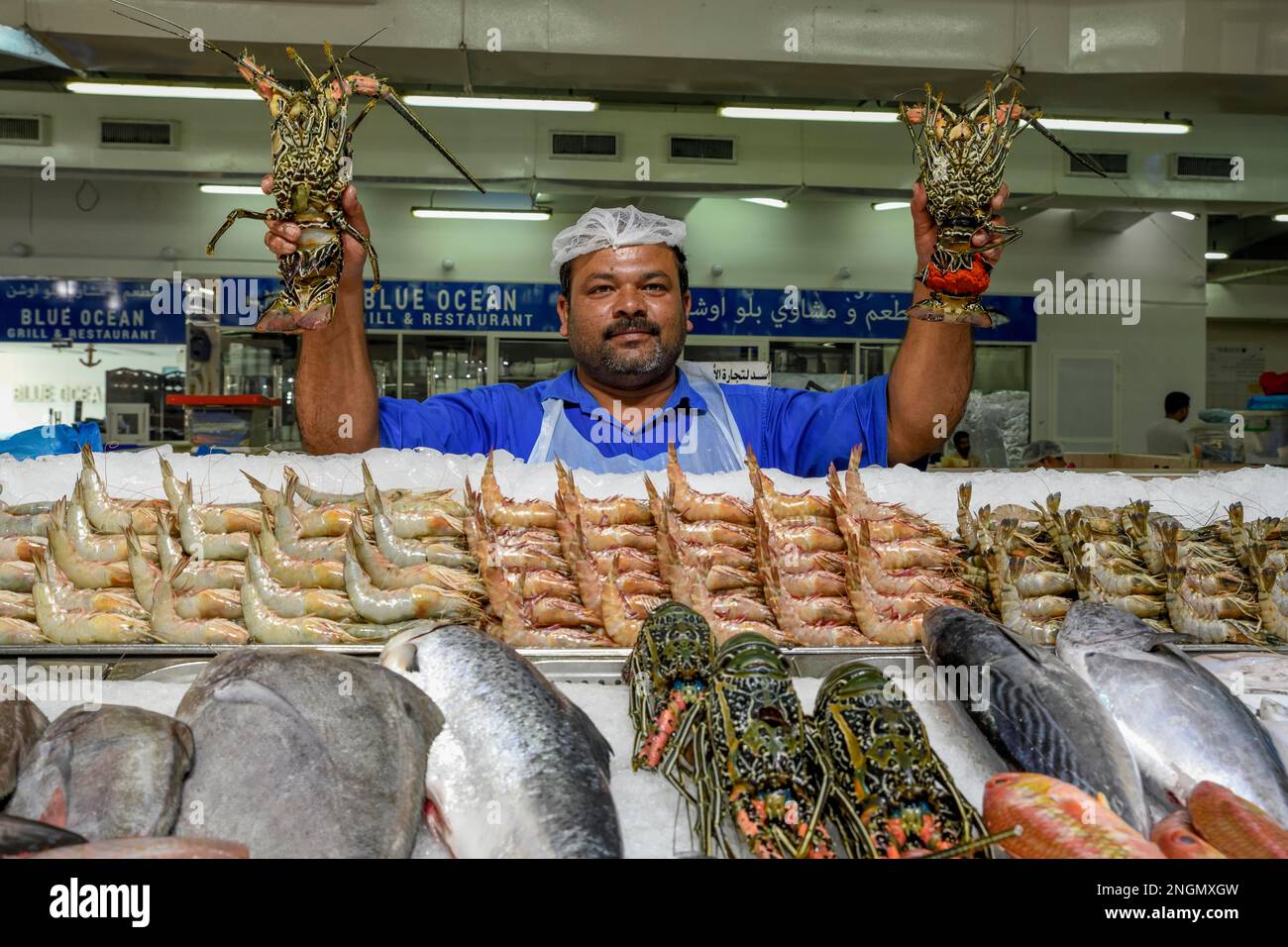 Seller on the fish market with two lobsters, Abu Dhabi City, Emirate of Abu Dhabi, United Arab