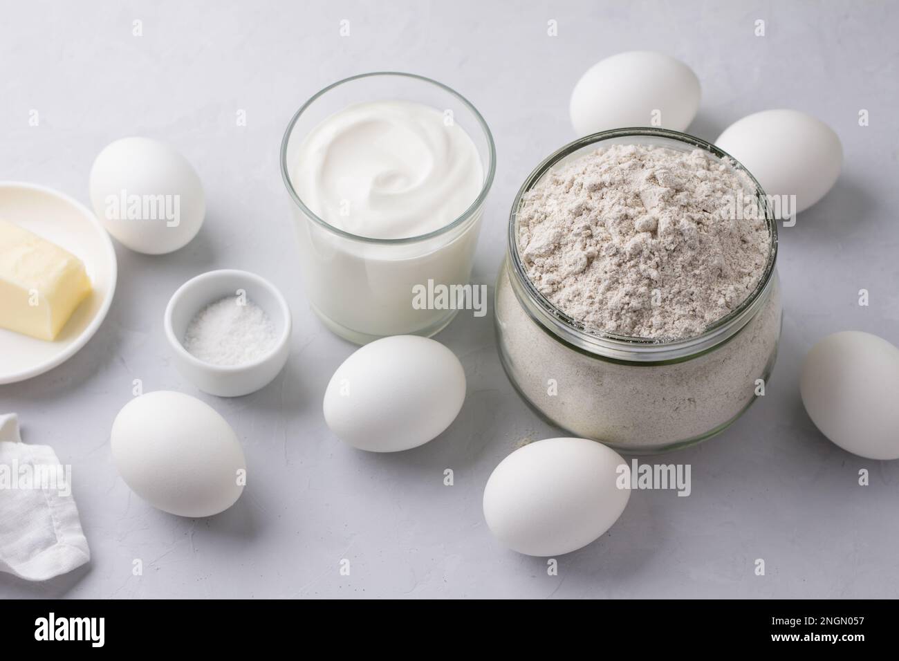 Ingredients for homemade rye pies with egg: rye flour, sour cream, eggs and butter on a light gray background, top view, selective focus Stock Photo