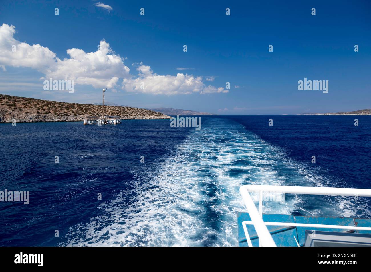 View of the sea line and ship waves as the local ferry boat is leaving the island of Iraklia, in Lesser Cyclades, Greece. Stock Photo