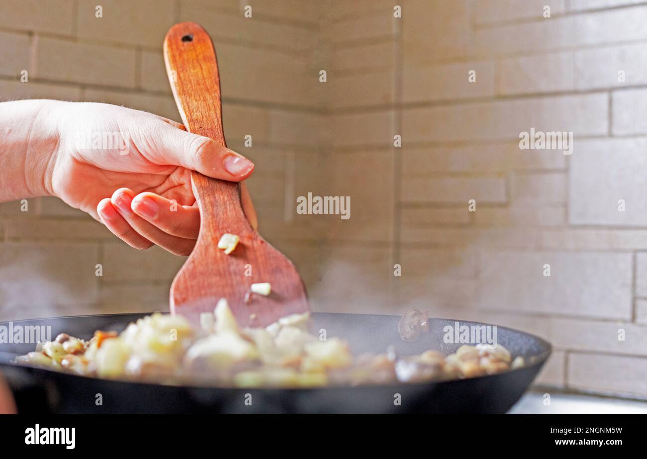 homemade dinner and mix vegetables and mushrooms in a hot pan with a wooden kitchen spatula. Diet Stock Photo