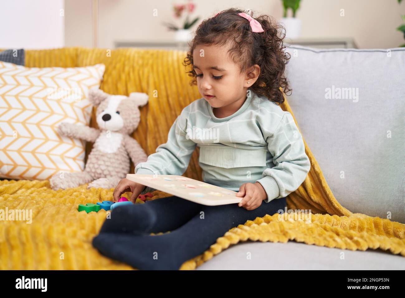 Adorable hispanic girl playing maths game sitting on sofa at home Stock ...