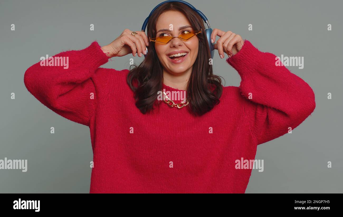 Happy pretty woman in headphones listening music and dancing disco ...