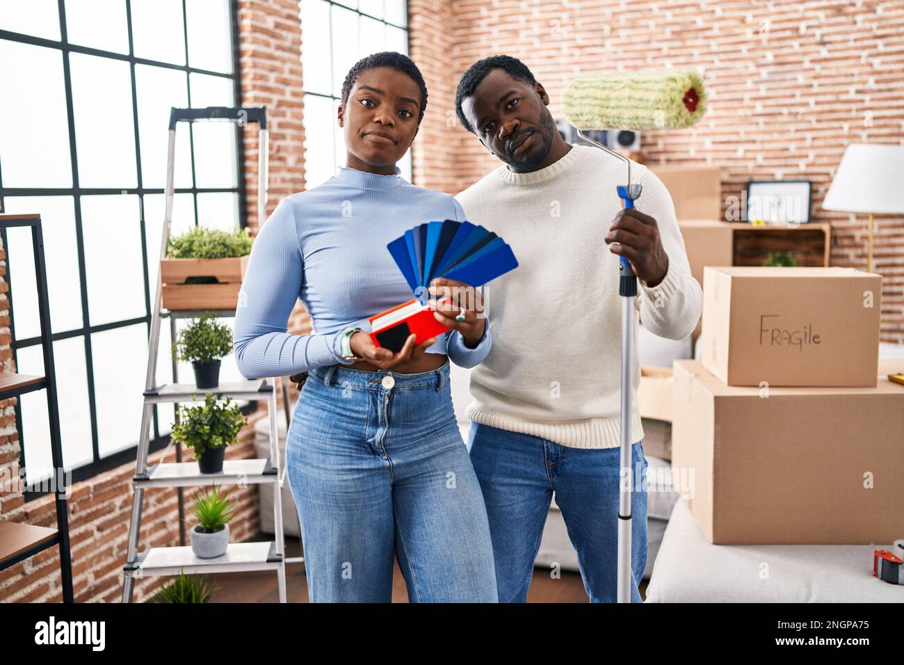 Young african american couple moving to a new home choosing walls color ...
