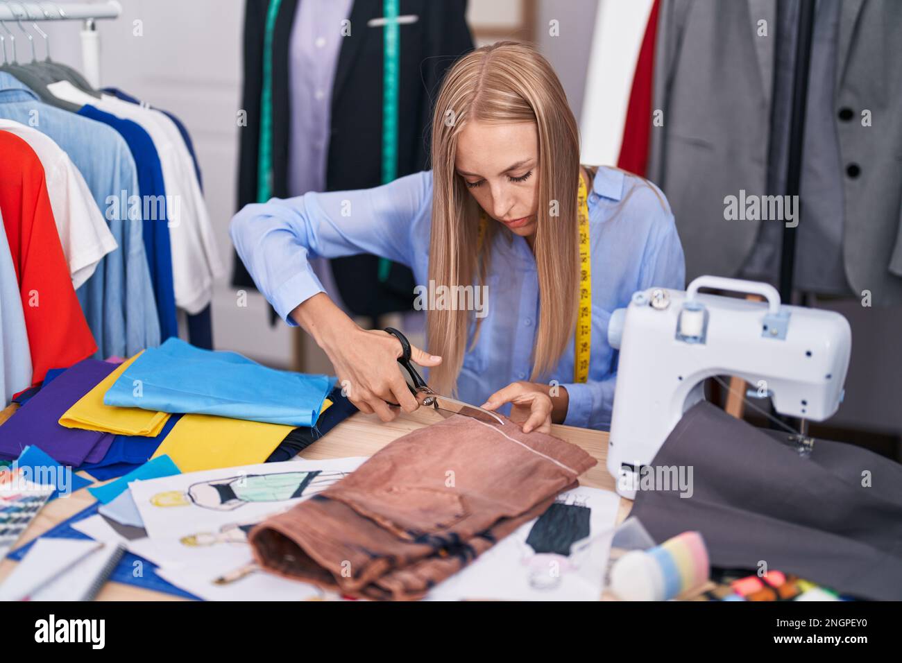Young blonde woman tailor cutting jeans at tailor shop Stock Photo Alamy