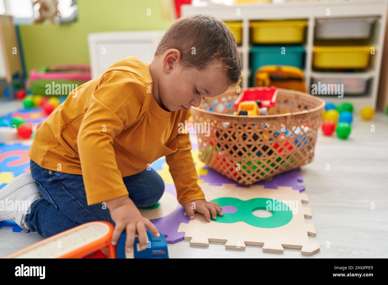 Adorable caucasian boy playing with truck toy sitting on floor at ...