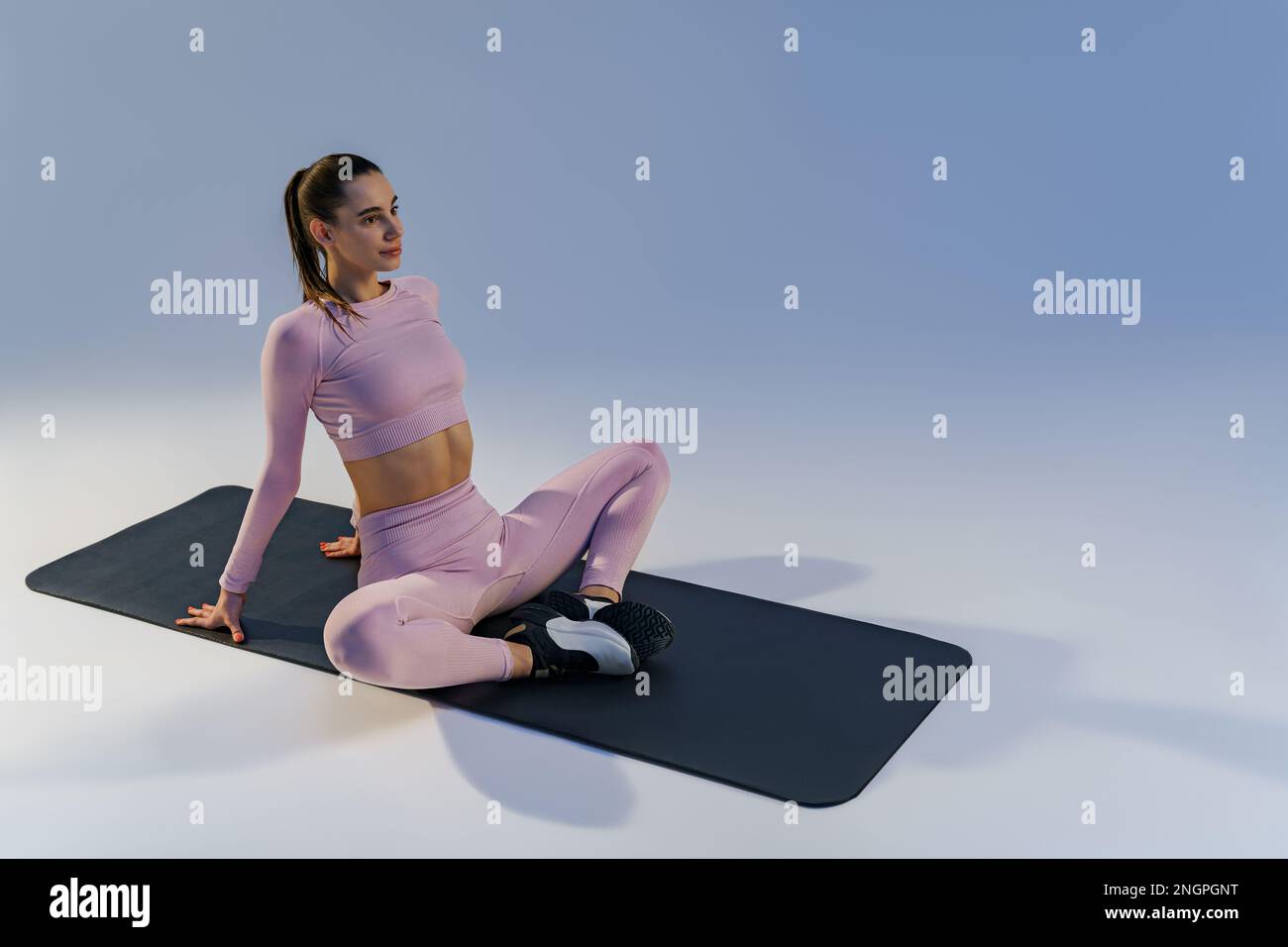 Woman wearing sportswear doing stretching exercises on yoga mat on ...