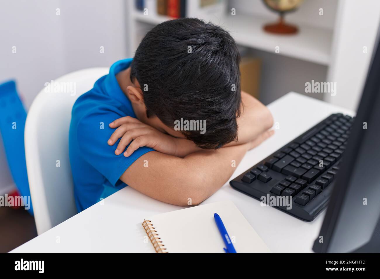 Adorable hispanic boy student using computer with stressed expression ...