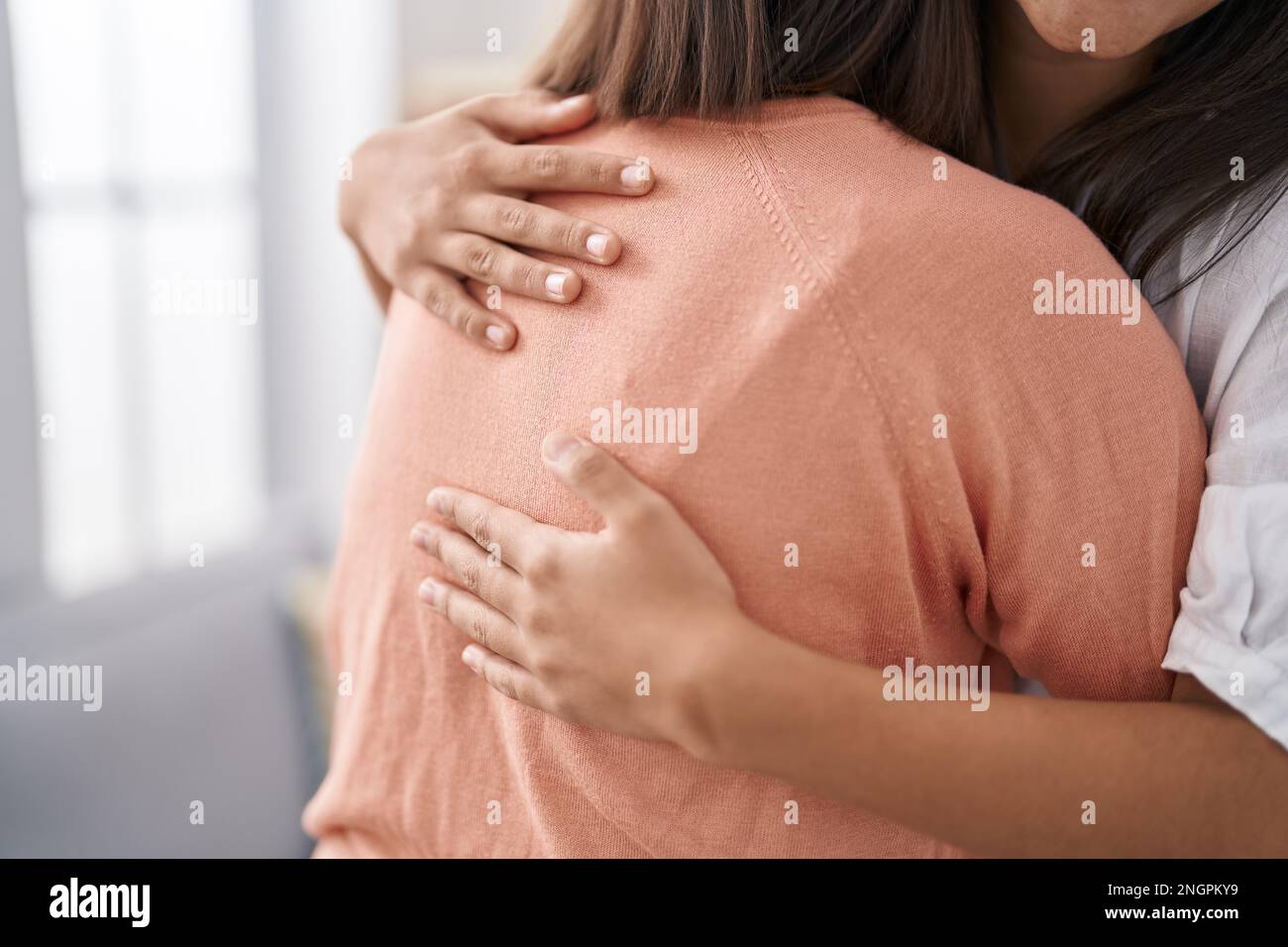 Two women mother and daughter hugging each other at home Stock Photo