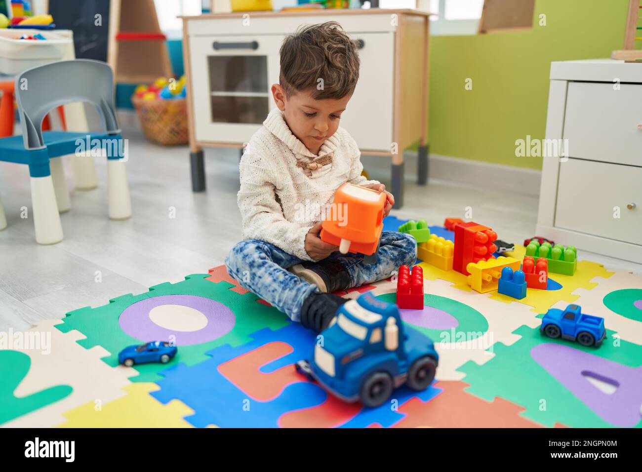 Adorable hispanic toddler playing with cars toy sitting on floor at ...