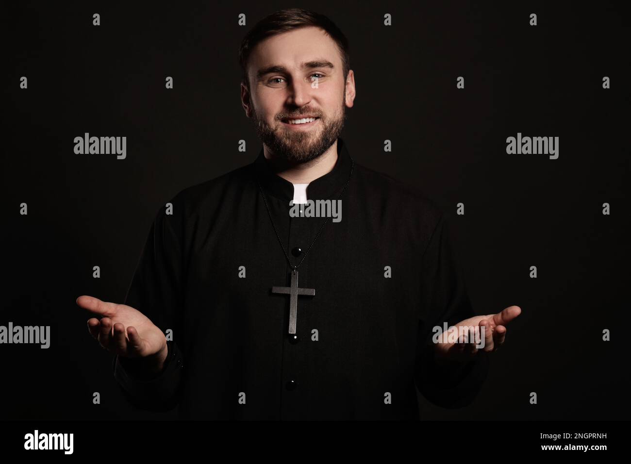 Priest wearing cassock with clerical collar on black background Stock Photo