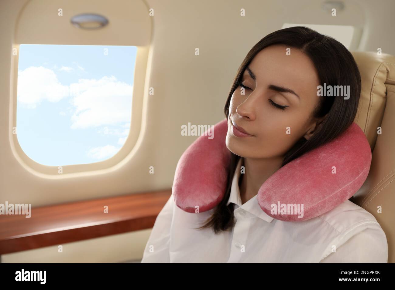 Young woman with travel pillow sleeping in airplane during flight Stock Photo Alamy