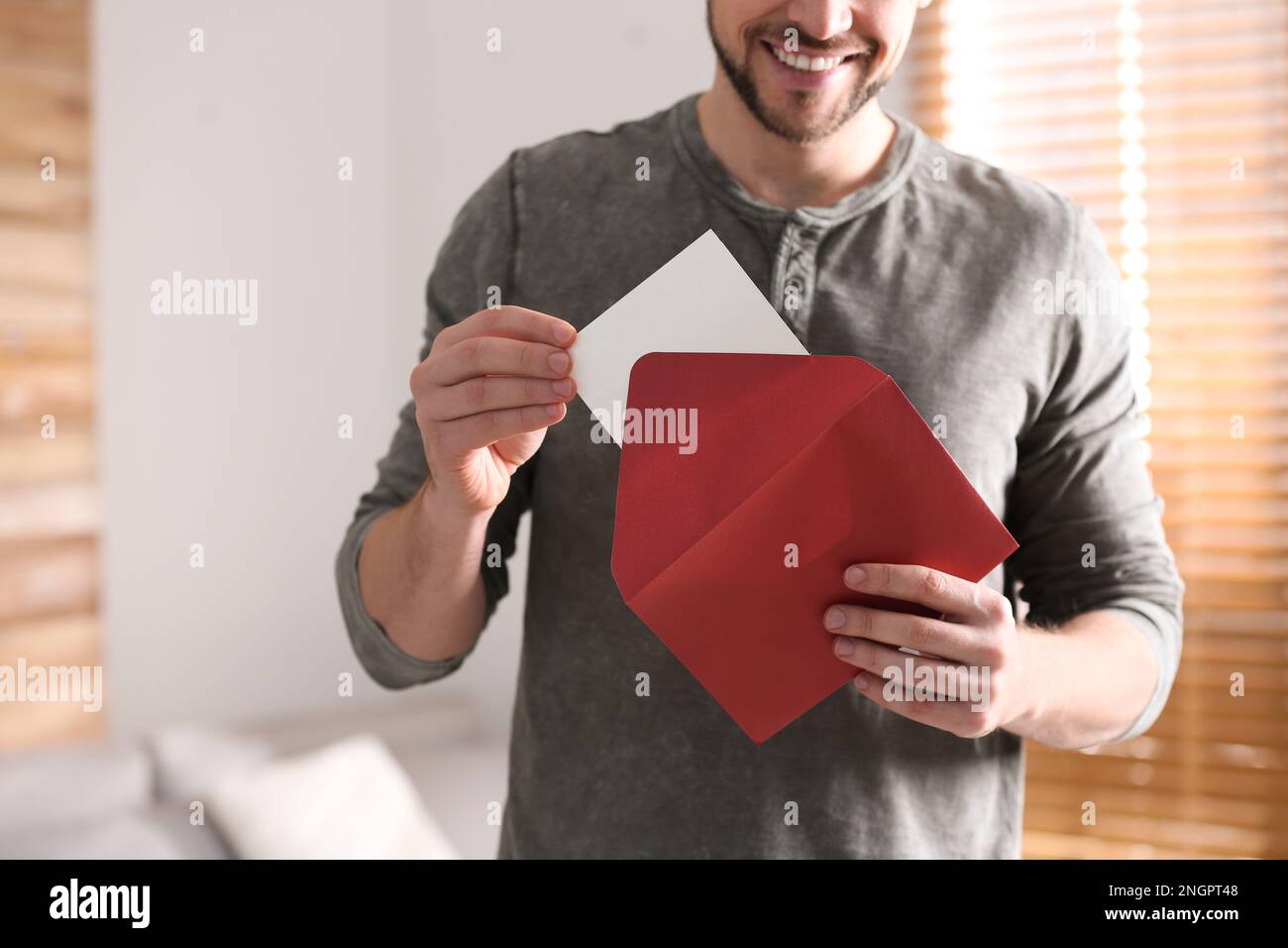 Man holding envelope with blank greeting card indoors. closeup Stock Photo