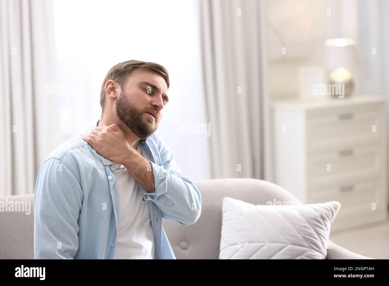 Man suffering from neck pain at home. Bad posture problem Stock Photo ...