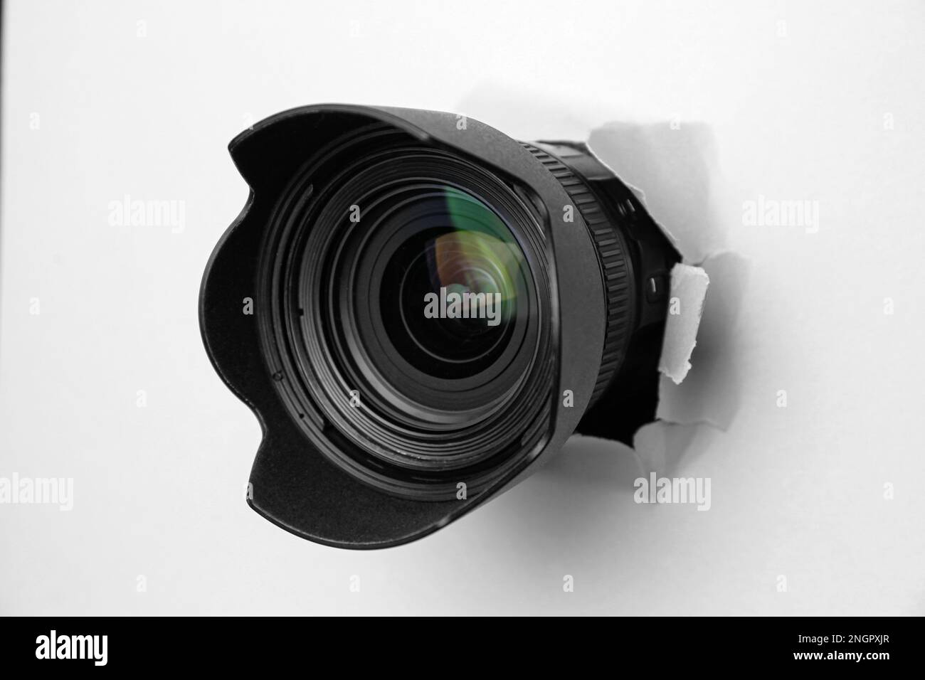 Hidden camera lens through torn hole in white paper Stock Photo Alamy