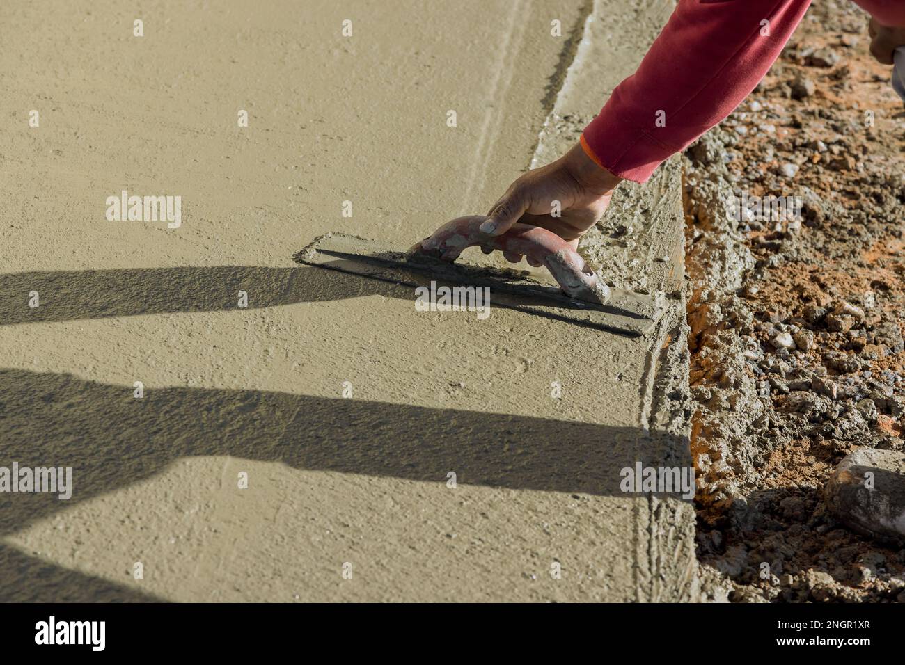 Using trowel worker plasters wet concrete cement floor after concrete