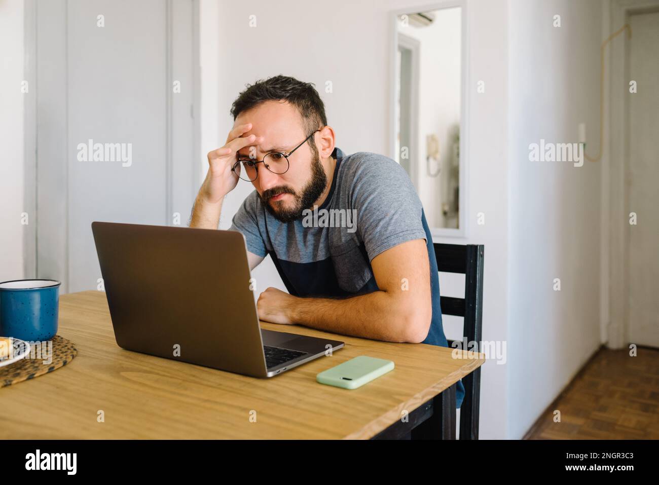 Man using his laptop holding his head. Stock Photo