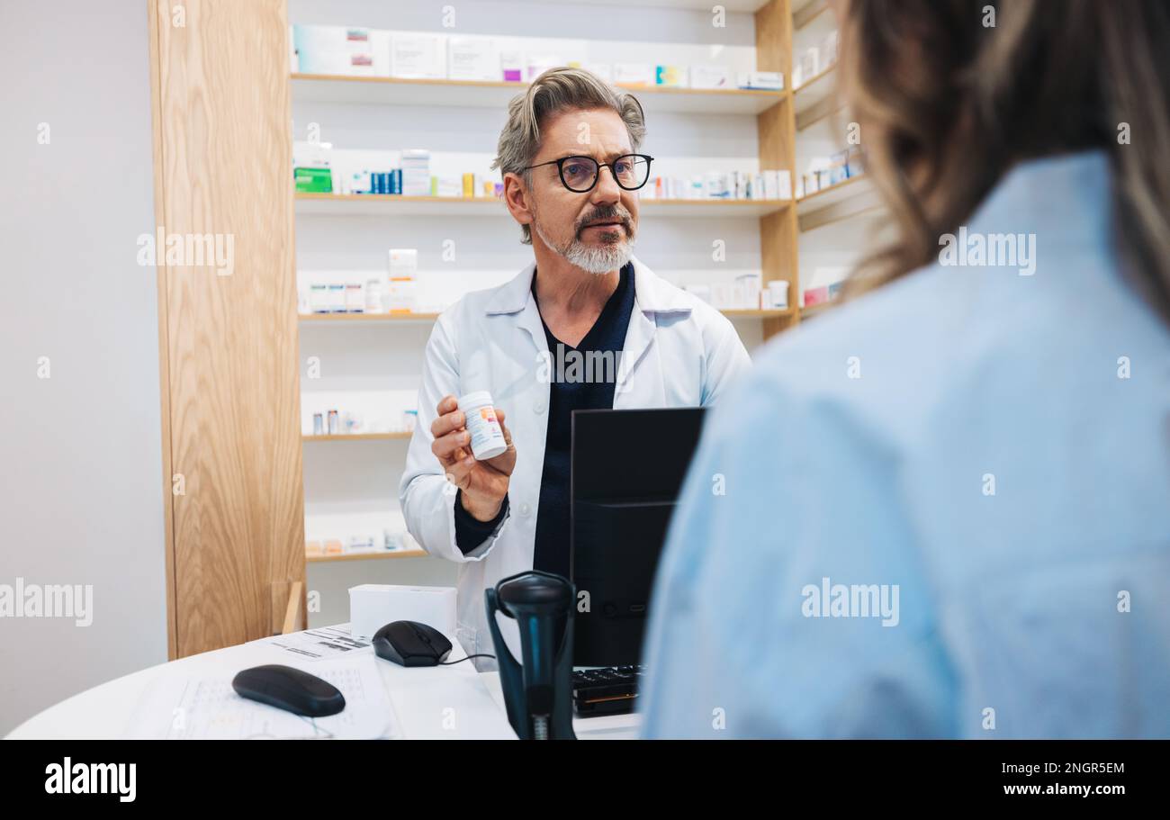 Mature pharmacist assisting a patient over the counter in a drug store