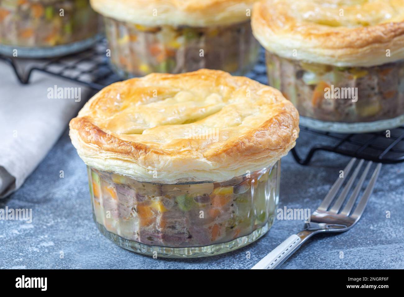 Individual beef pot pies or deep dish pies in ramekin and on a cooling