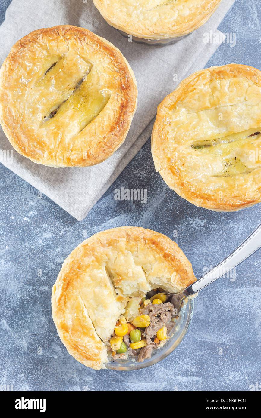 Small beef pot pies or deep dish pies in ramekin, crust broken open to