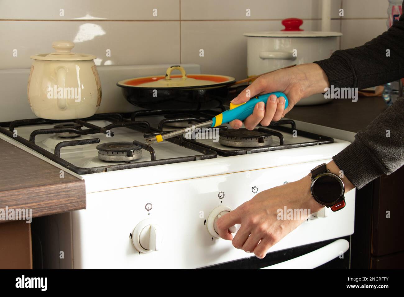 A girl with a lighter light a gas stove in the kitchen of a house in
