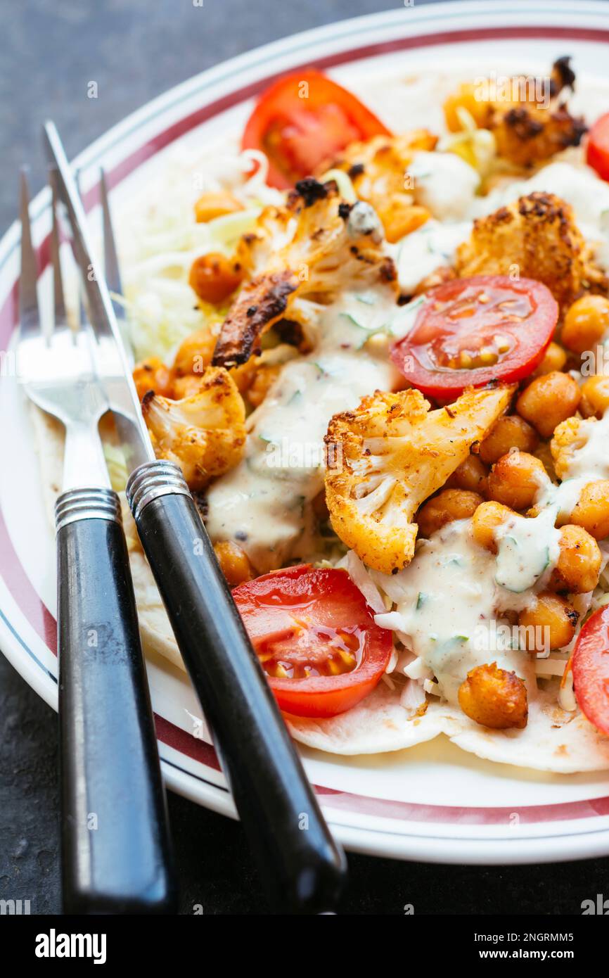 Open-faced vegetable burrito with flour tortillas, cabbage slaw, roasted cauliflower, roasted chickpeas and a spicy sauce. Stock Photo