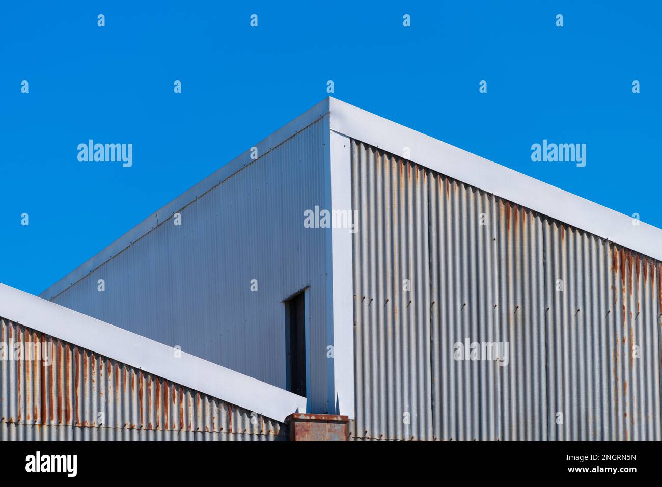 Metal corrugated iron factory wall and rooftop with a blue cloudless sky in Castlemaine Australia. Stock Photo