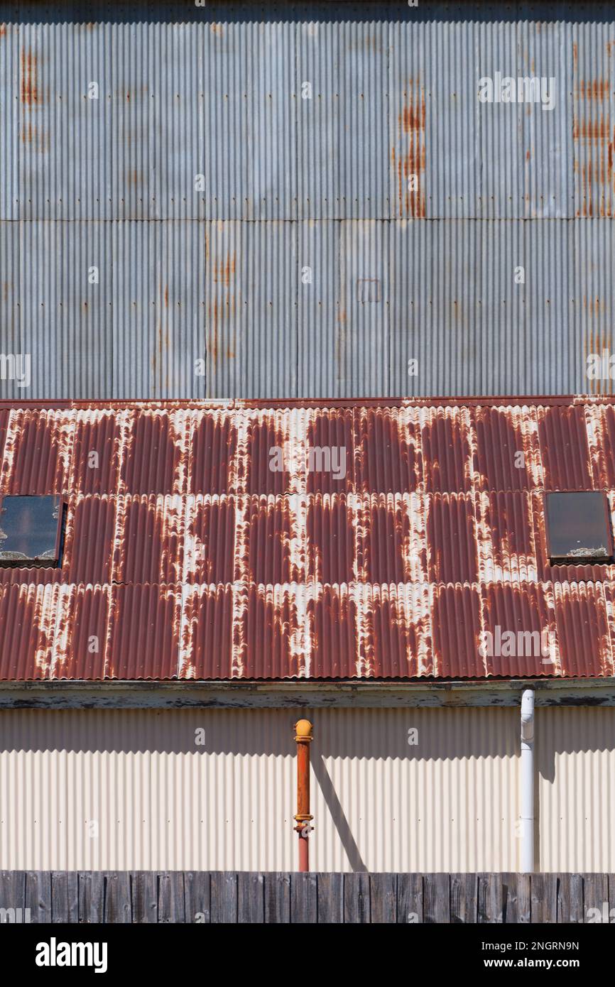 Background metal texture showing a corrugated iron factory wall, rusted roof and wall pipes in Castlemaine Australia. Stock Photo