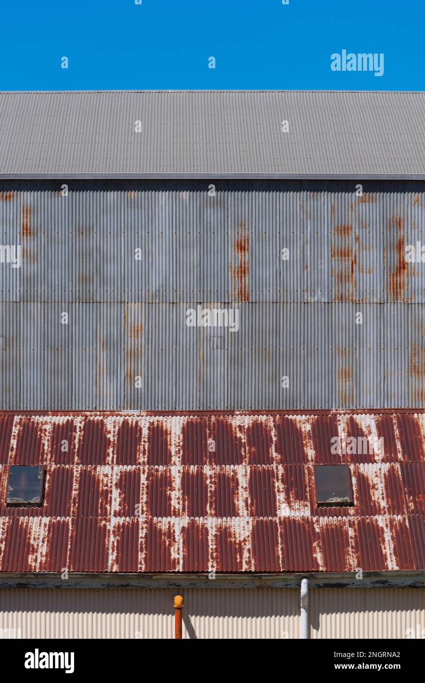 Metal corrugated iron factory wall and rusted roof with blue sky in Castlemaine Australia. Stock Photo