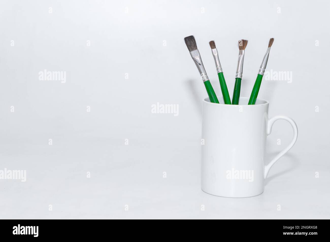 Paint brushes kept standing in a cup with white background and copy