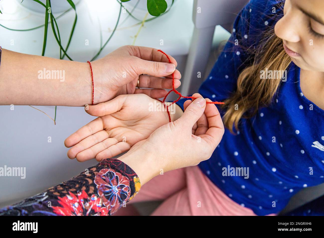 The mother ties a red thread to the child hand. Selective focus. Kid