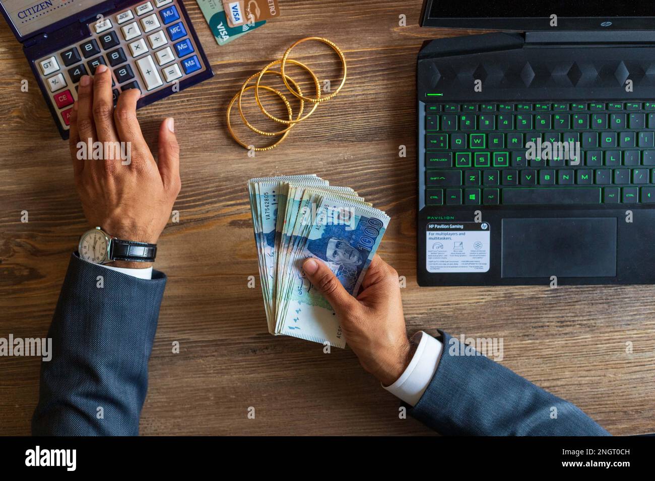 Business man hand dealing with Pakistani Ruppee Currency notes and gold for budget Saving money investment and financial accounting management or grow Stock Photo